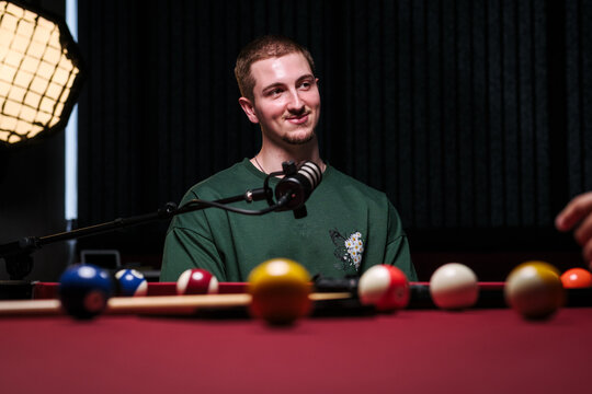 Young man recording live podcast at studio table