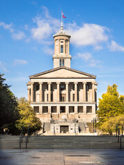 The state capital building in Nashville, TN, from War Memorial Plaza. Bathed in early morning sunlight with blue sky and clouds.