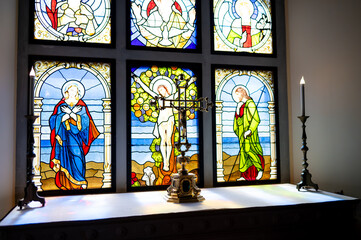 Colorful stained glass window depicting saints in traditional Christian imagery inside a church