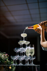 Bride and groom pour champagne into a sparkling tower, celebrating their union. This elegant...