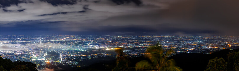 Aerial view of city skyline landscape at night with misty clouds over the illuminated cityscape...