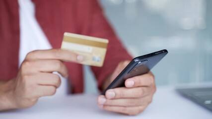 Close up of male hands using phone to make online transaction with credit card at desk in business office. Shopper businessman in red shirt makes digital payment, pays bills, e-commerce, e-shopping - Powered by Adobe