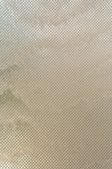 Water streams down glass covered with metal mesh, catching light and texture. The effect is cool, modern, and quietly captivating.