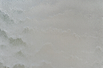 Water streams down glass covered with metal mesh, catching light and texture. The effect is cool, modern, and quietly captivating.