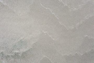 Water streams down glass covered with metal mesh, catching light and texture. The effect is cool, modern, and quietly captivating.