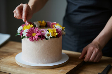 artisan decorator applying vibrant blooms to vegan cake top, organic cake decorating