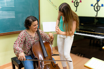 Music teacher helping student playing cello in classroom © Alfonso Soler