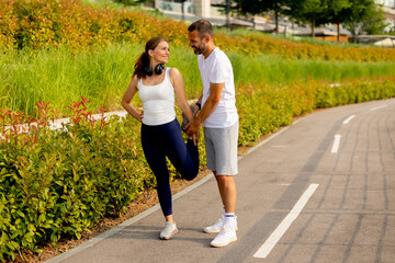 Outdoor stretching session in a vibrant park as a fitness trainer guides a client towards better...
