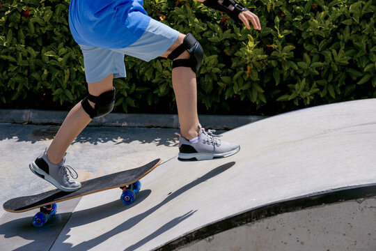 Teen riding skateboard on ramp in safety gear