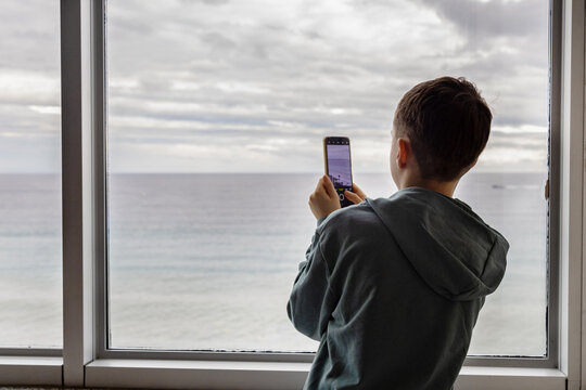 Young boy gazing at ocean, capturing moments by window