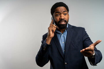 Confused Black businessman talking on phone, seeking explanation, isolated on white background