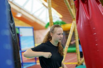 Obraz premium Young girl practicing her punches in a colorful indoor play area during afternoon hours