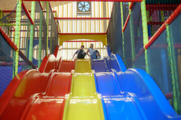 Kids enjoy playful fun sliding down colorful slides in a vibrant indoor playground during afternoon hours
