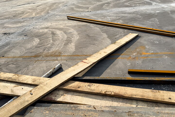 Scattered construction planks and metal beams on dusty concrete surface with minimalistic industrial aesthetic