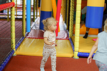 Toddler exploring colorful indoor play area filled with soft obstacles and interactive activities in the afternoon
