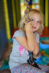 Child enjoys swinging indoors at a colorful play area with soft flooring and various toys available