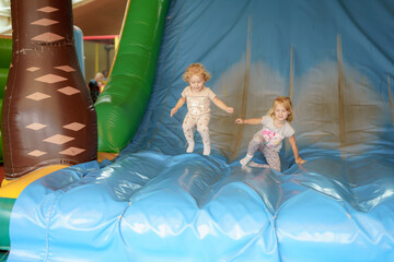 Children enjoying a fun day of bouncing and sliding on an inflatable play structure at a family entertainment center