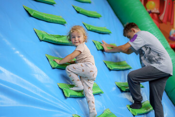 Young child enjoys climbing wall with adult companion at indoor play center