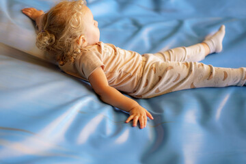 Toddler enjoying time on a soft blue surface while wearing cozy pajamas in a bright room