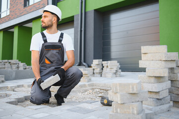 The master in gloves lays paving stones in layers. Garden brick pathway paving by professional...