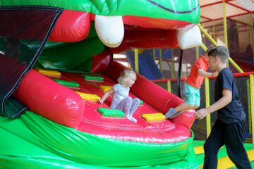 Kids enjoying fun at a colorful inflatable play structure in an indoor amusement center during a sunny afternoon