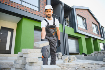 worker lay paving tiles, construction of brick pavement, men's hands in gloves.