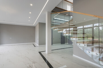 Obraz premium Modern design of the lobby of a luxury mansion. Stairs with wooden steps and glass railings. Unfurnished.