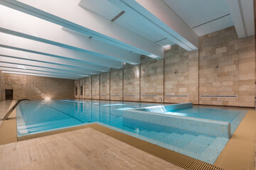 Magnificent design of the pool with convenient steps for descent. The room is decorated with beige tiles.