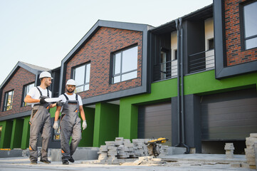 Two builders on the background of new cottages. The work is done