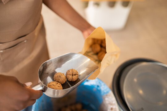 Organic grocery clerk scooping walnuts into paper bag