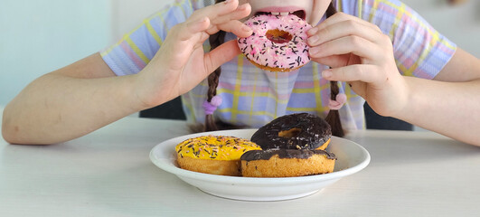 A young girl sits at a table and eats a sweet donut