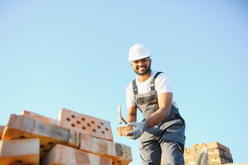 Installing brick wall. Indian Construction worker in uniform and safety equipment have job on...