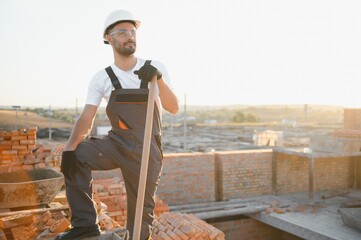 Man bricklayer installing bricks on construction site