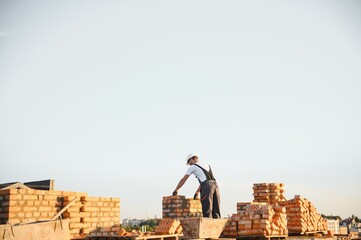 Installing brick wall. Construction worker in uniform and safety equipment have job on building