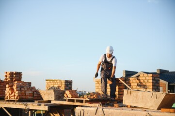 Man bricklayer installing bricks on construction site