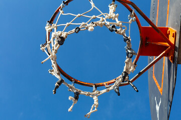 Basketball hoop with damaged net under blue sky