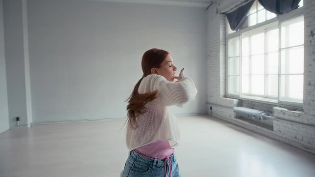 Sequence of shots of Caucasian female zoomers in urbanwear practicing dance moves on camera in studio with minimalist interior