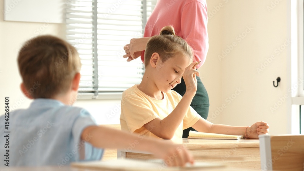 Poster beautiful teacher explaining test while caucasian boy doing classwork and listening explanation. cut