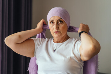 Focused woman tying lilac scarf with confidence