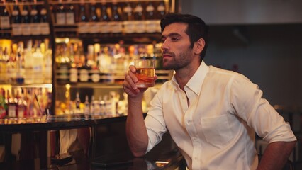 Smart man in white shirt drinking cocktail Old fashioned waiting friends or couple while chatting on smartphone in special party beverage vibrant at nightclub on Friday meeting night time. Vinosity.