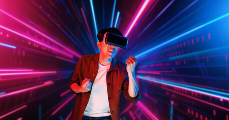 Smart male gamer with VR glasses celebrating for winning the game with glowing neon light. Excited...