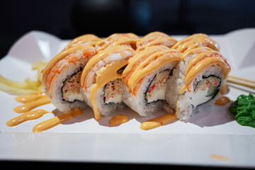 Fresh sushi rolls drizzled with spicy mayonnaise on a white plate