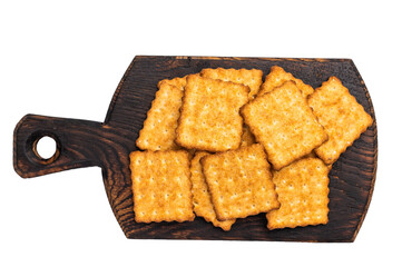 Heap of square salty crackers on wooden board isolated on white background, top view.