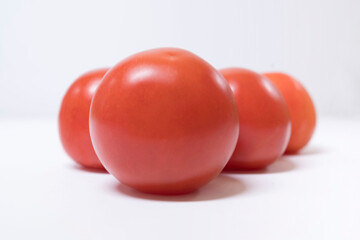 Closeup of four red tomatoes on a black background.