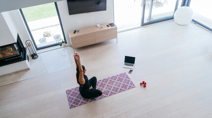 Young Beautiful Female Exercising, Stretching and Practising Yoga with Trainer via Video Call...