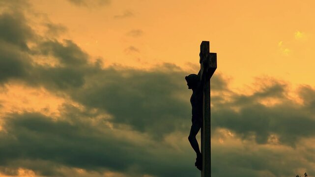 Old stone monument representing Jesus Christ crucifixion on Golgotha hill, 4K, dramatic clouds time lapse, at sunset