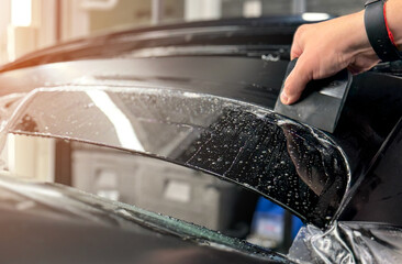 Wrapping protective film on the car. A car wrapping specialist applies a matte polyurethane film to...