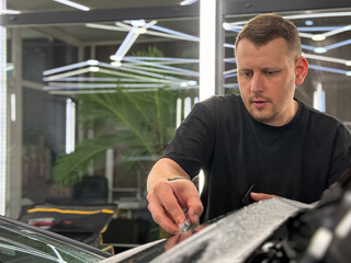 A car wrapping specialist applies a matte polyurethane film to the car. Selective focus. PPF...