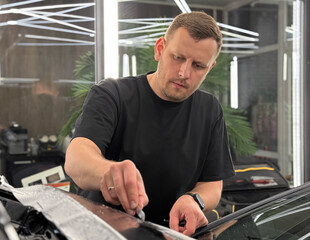 A car wrapping specialist applies a matte polyurethane film to the car. Selective focus. PPF...