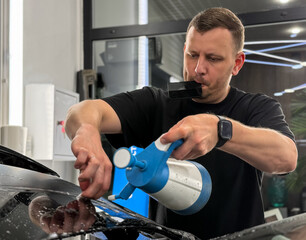 A car wrapping specialist applies a matte polyurethane film to the car. Selective focus. PPF...